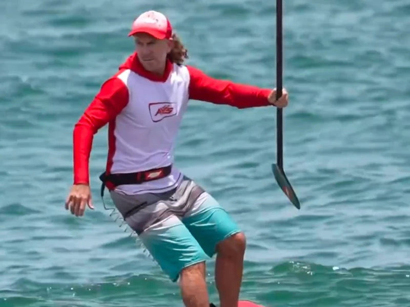 Nick O’Bea riding a SUP foil, standing on a red board with the paddle in hand