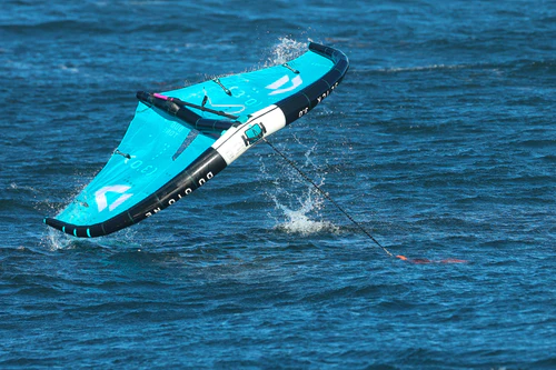 Kaohi Anchorman sea anchor securing a wing foil on the water — bright orange anchor keeping the wing stable and preventing drift during foiling sessions.